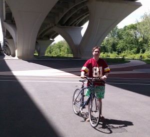 Aubrey Nesbitt takes a break from riding his bicycle below the Woodrow Wilson Bridge
