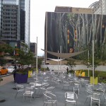 Tables and chairs outside, before a large wall mural